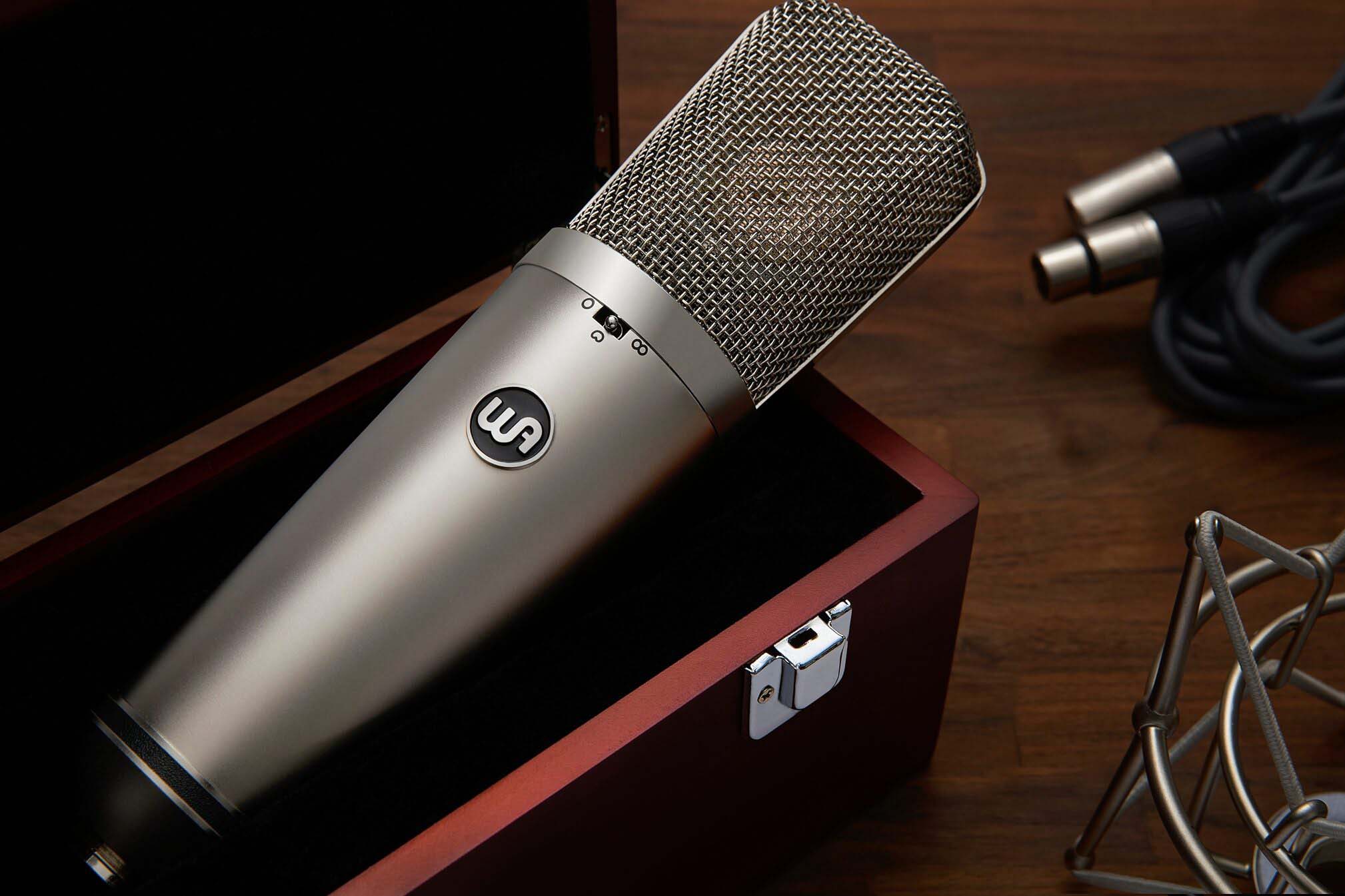 Warm Audio WA-67 Tube Large-Diaphragm Condenser Microphone, closeup view in a custom wooden box showing the edge of the shockmount and xlr cable in the background.
